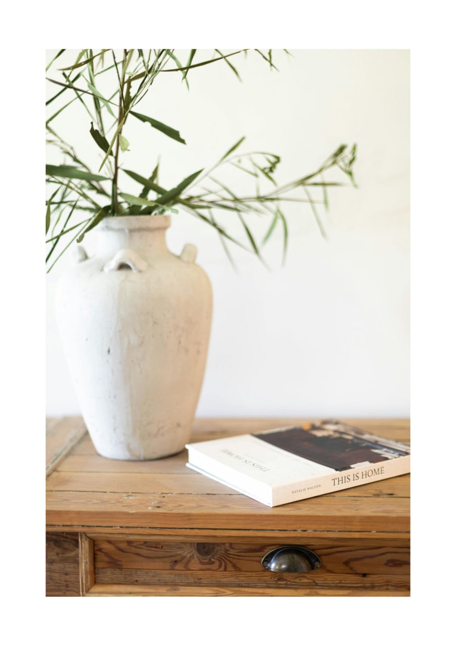 Ceramic vase with greenery on wooden desk